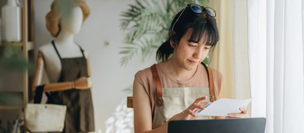 Female business owner checking letter in front of a laptop